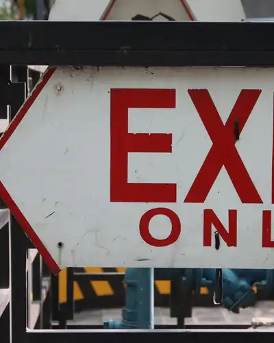 A red and white Exit Only sign with an arrow, mounted on a railing