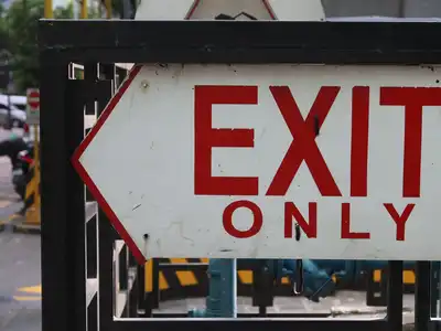 A red and white Exit Only sign with an arrow, mounted on a railing