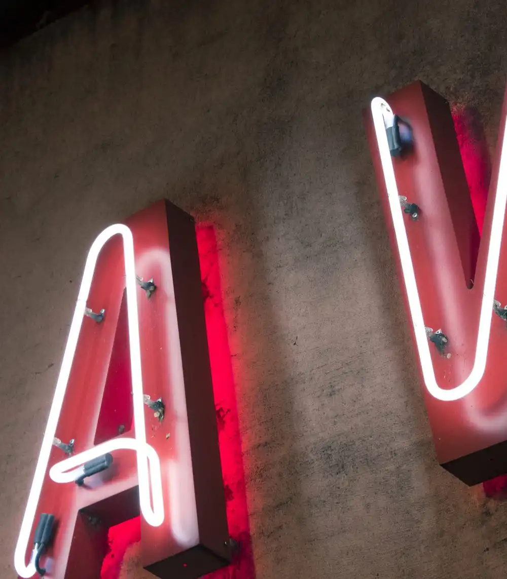 Red neon letters A and V mounted on a dark wall
