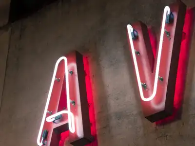 Red neon letters A and V mounted on a dark wall