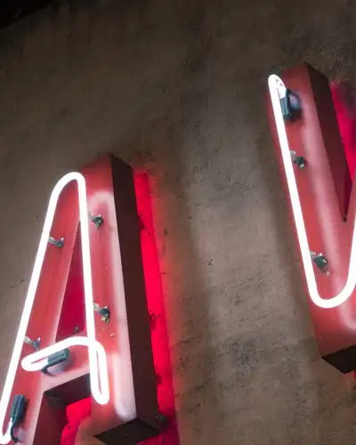 Red neon letters A and V mounted on a dark wall