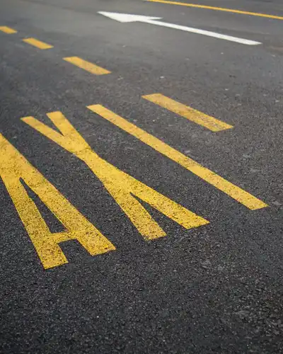 The word TAXI painted in large yellow letters on asphalt