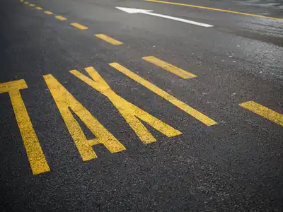The word TAXI painted in large yellow letters on asphalt