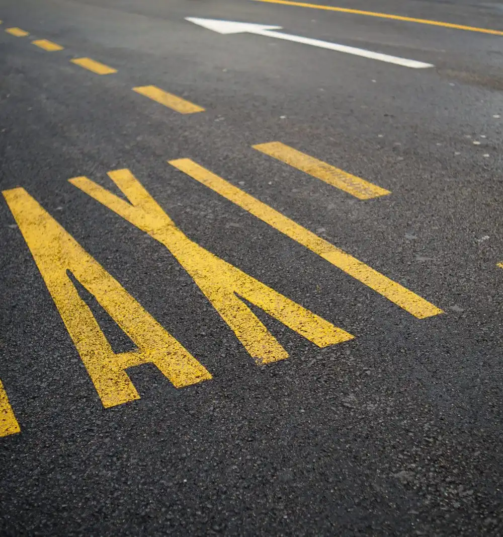 The word TAXI painted in large yellow letters on asphalt